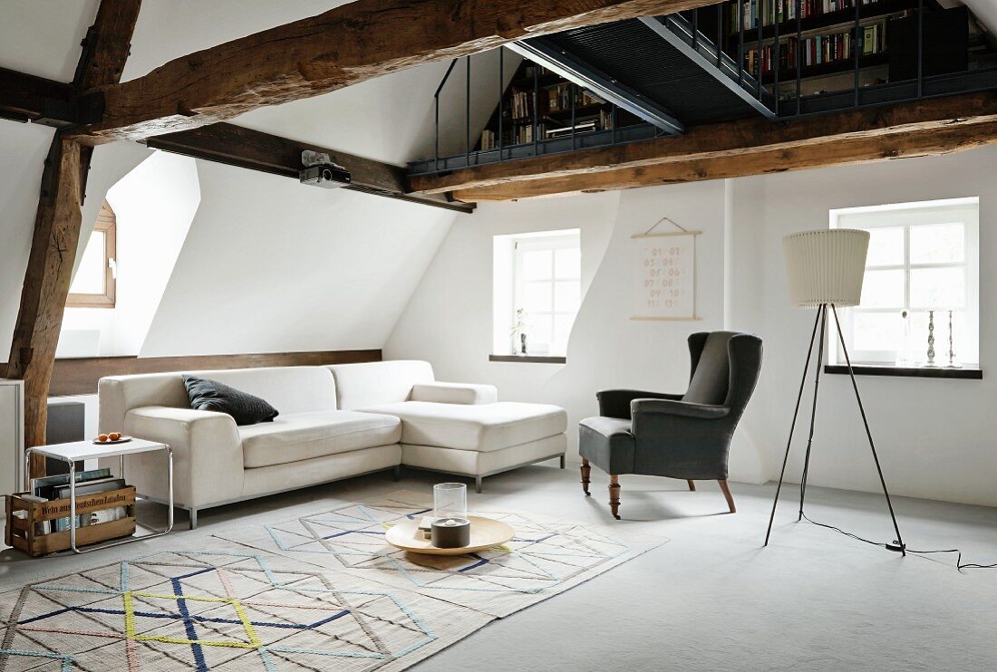 Sofa, Ohrensessel und Klassiker Beistelltisch, davor Teppich mit geometrischem Muster, darüber offene Galerieebene