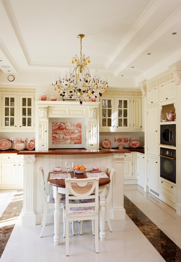 Dining area in front of counter in white, country-house kitchen in grand interior