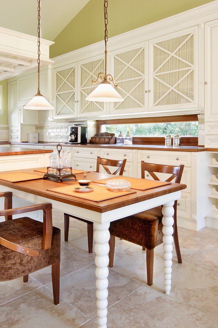 Platzsets auf Tisch mit gedrechselten Beinen in Weiß lackiert, Stühle mit gepolsterten Sitzflächen in Landhausküche