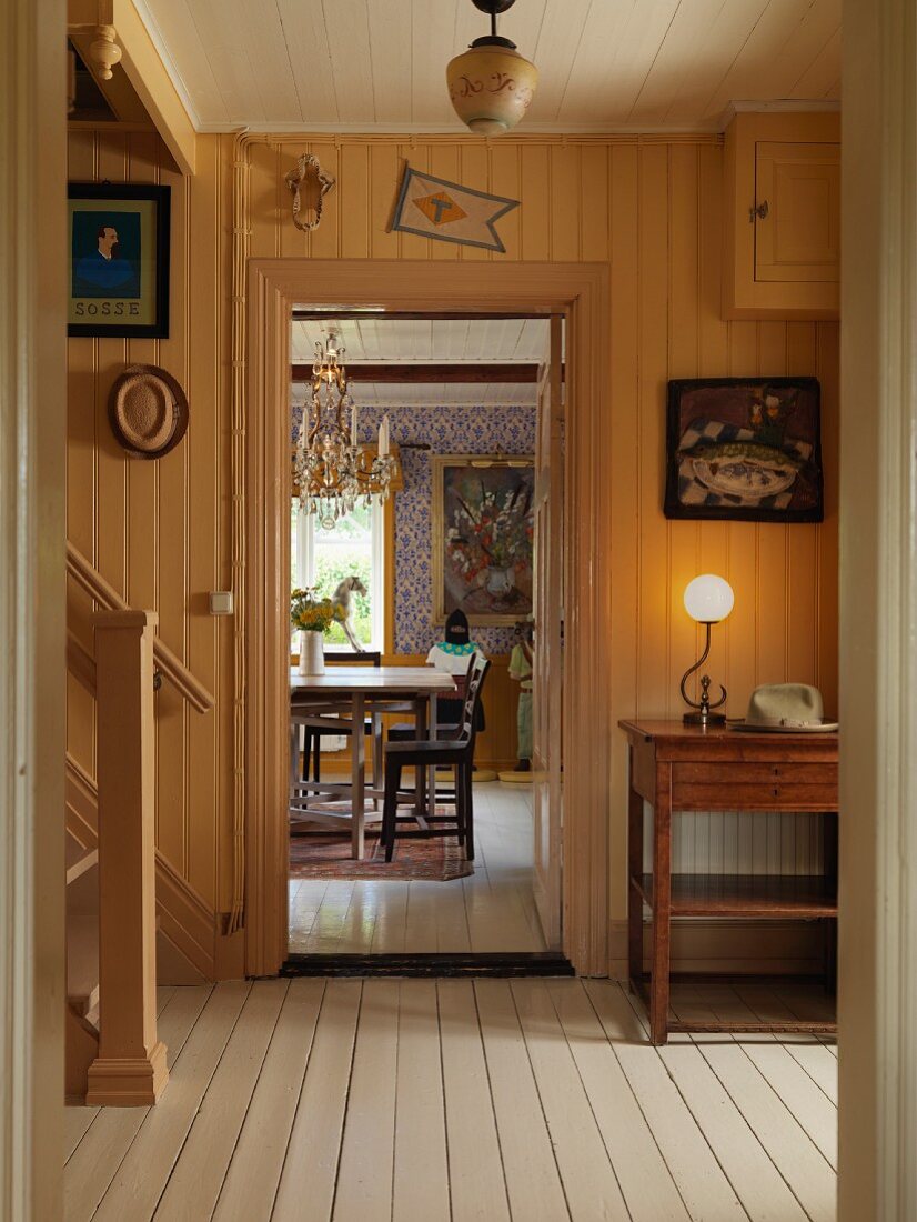 Blick durch Vorraum mit teilweise sichtbarer Treppe, ins Esszimmer auf Tisch und Stühle, in altem Landhaus