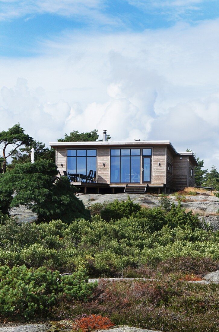 Modernes Sommerhaus aus Holz mit grossen Fensterflächen, am Hang