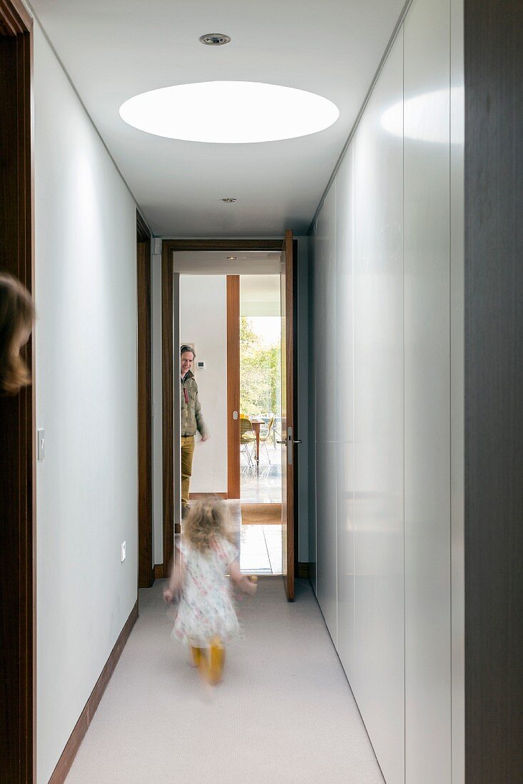 Family in narrow corridor with skylight and white fitted cupboards