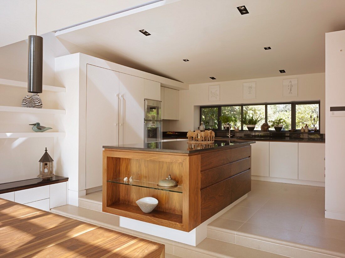 Solid wood kitchen counter on platform in open-plan, white designer kitchen
