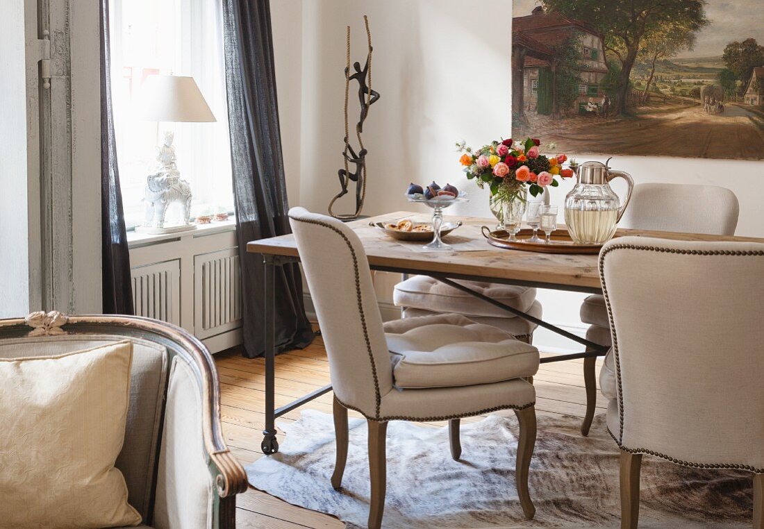 Chairs with beige upholstery at rustic dining table in corner of traditional living room
