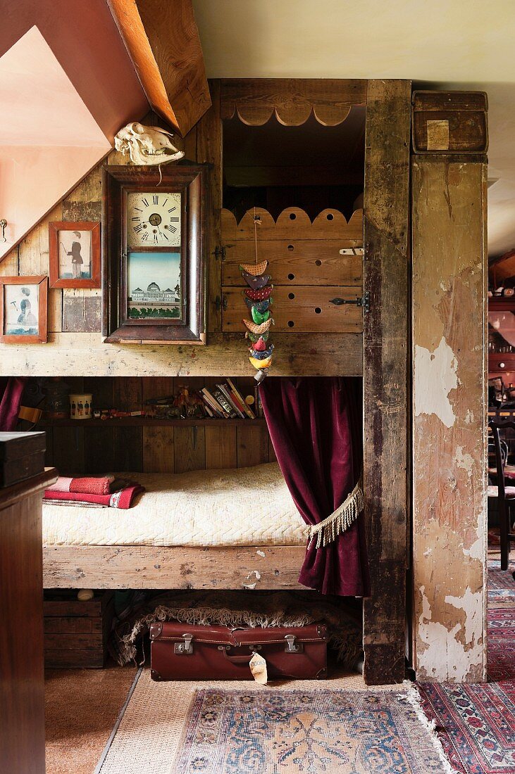Stockbett aus recyceltem Holz und antike Wanduhr in Vintage-Ambiente