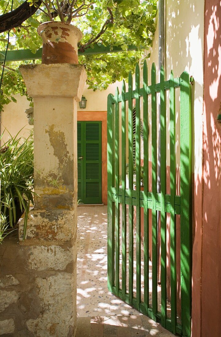 Grünlackiertes Eingangstor und Blick auf mediterranen Hauseingang mit ockerfarbener Fasche