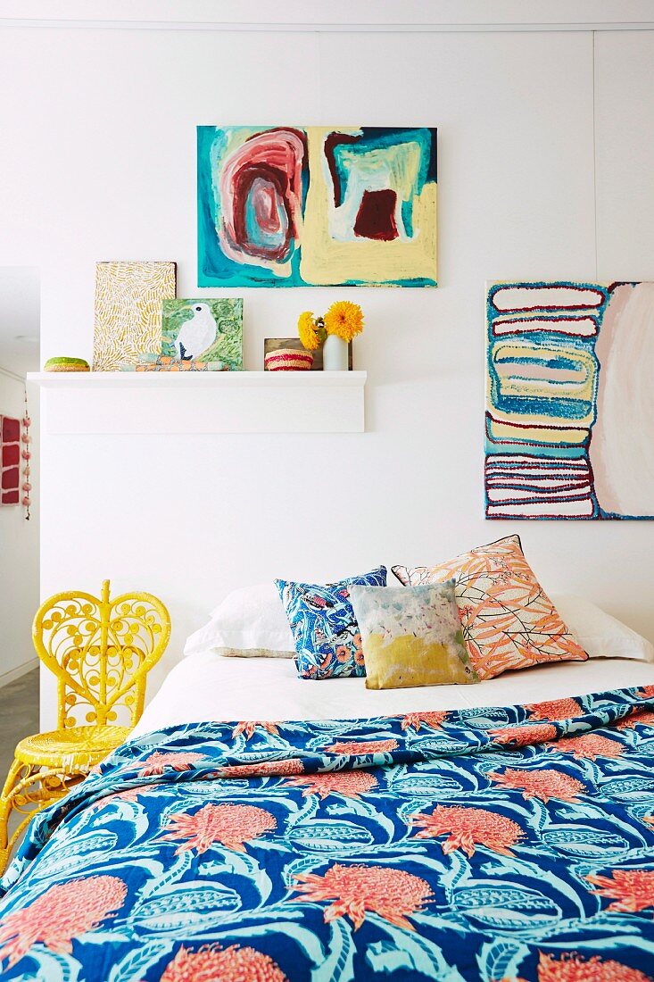Colorful bedroom with pictures and different patterned pillows and bedspread