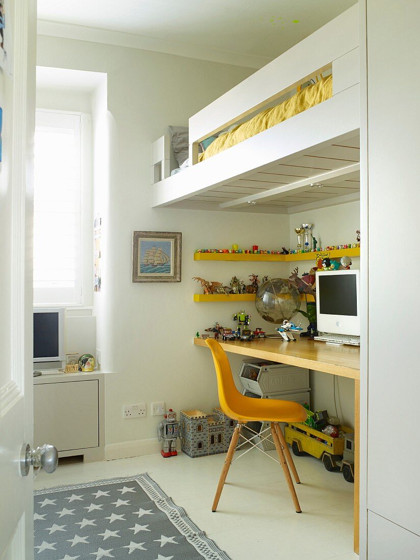 Yellow classic chair in front of floating desk below modern loft bed in child's bedroom