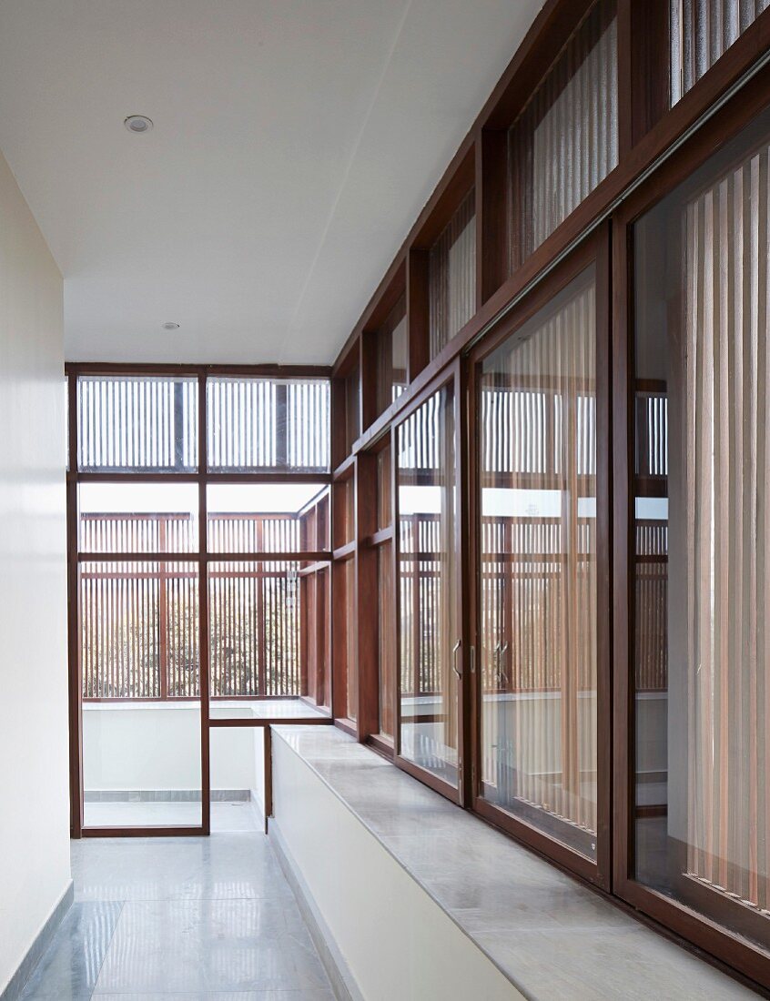 Gangflucht in modernem, indischem Wohnhaus mit durchgehenden Fensterfronten in Holzrahmenbauweise