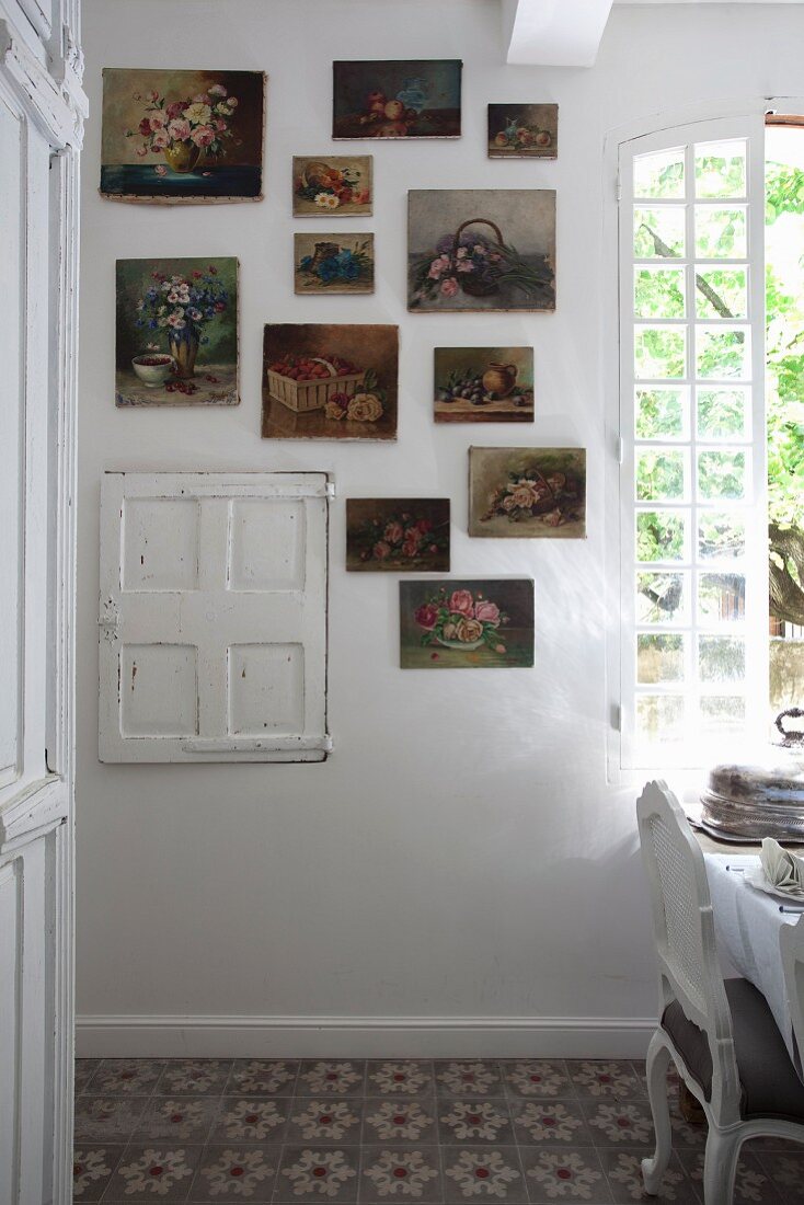 Gemäldesammlung mit Blumenmotiven an Wand neben Fenster, in ländlichem Esszimmer