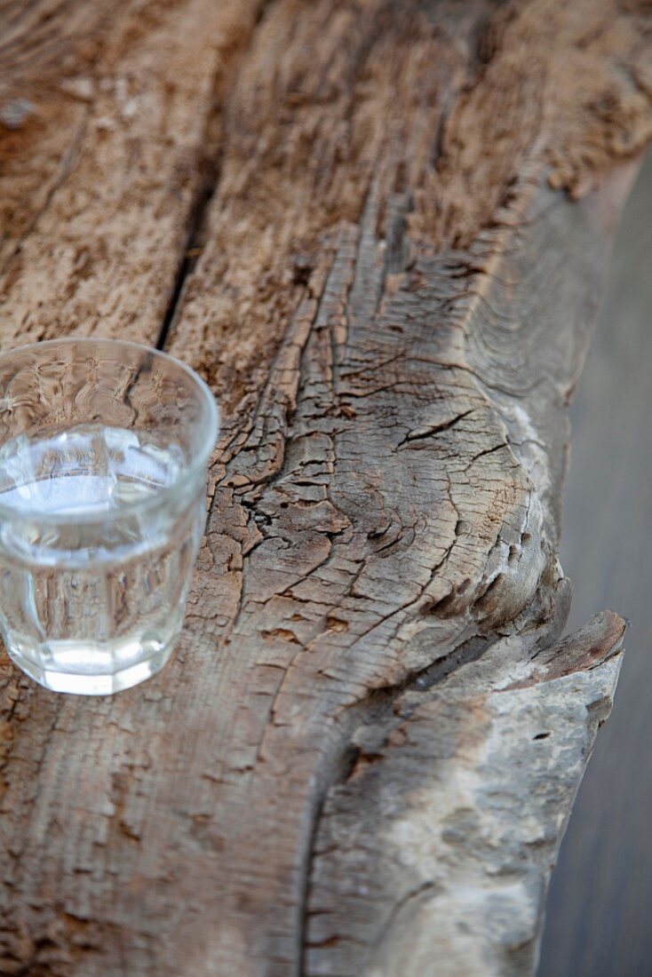 Wasserglas auf verwittertem Baumstamm