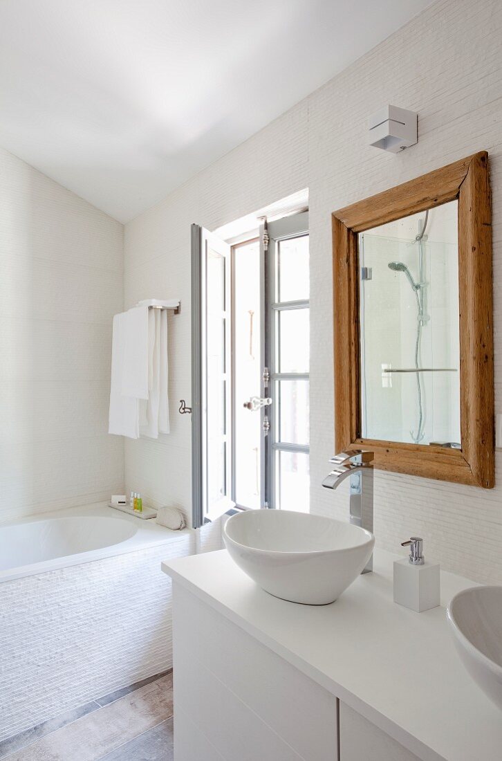 Waschtisch mit Waschschüsseln auf weißem Unterschrank, an Wand Spiegel mit hellem Holzrahmen, in ländlichem Bad