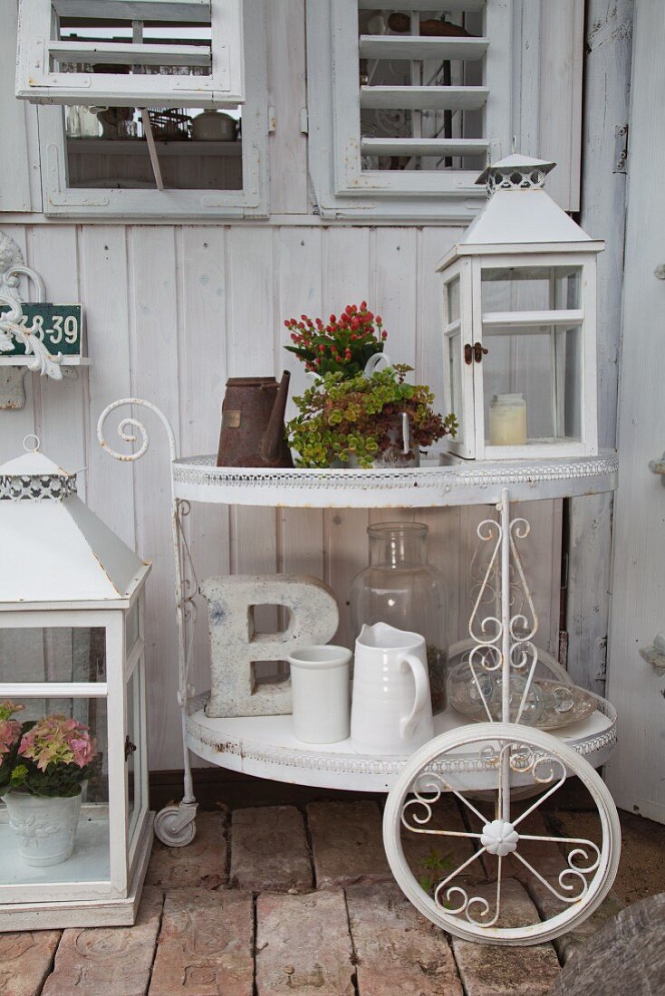 Weiß lackierter Vintage Teewagen mit Laterne, Blumentopf und weissen Krügen