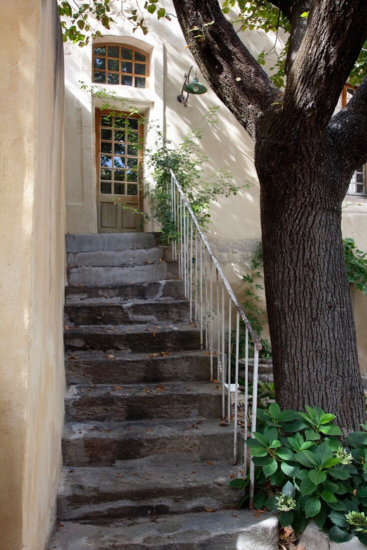 Weathered, stone exterior stairs with white metal balustrade in courtyard