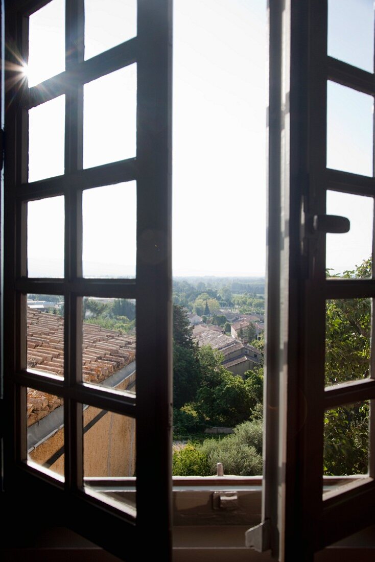 Halb geöffnete Sprossenfenster mit Ausblick auf mediterrane Landschaft