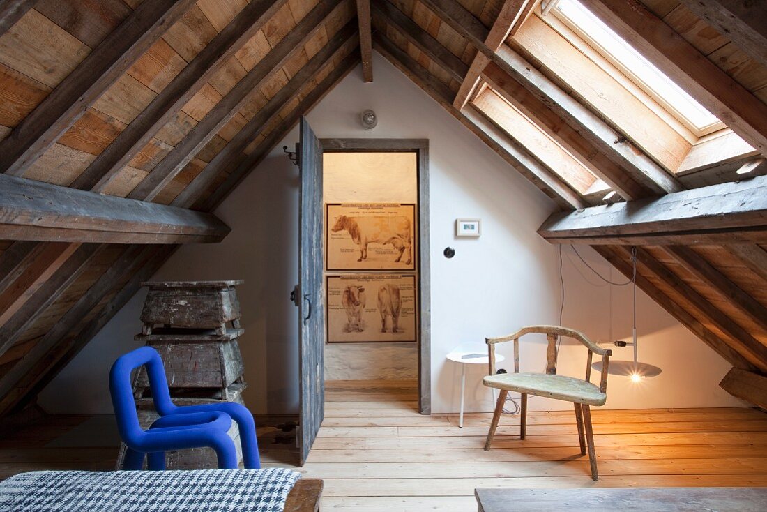 Blauer Schaumstoff-Stuhl und Holzstuhl in rustikalem Zimmer unter dem Dach