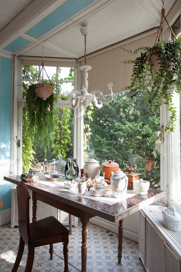 Crockery on table and antique wooden chair in window bay with view of garden