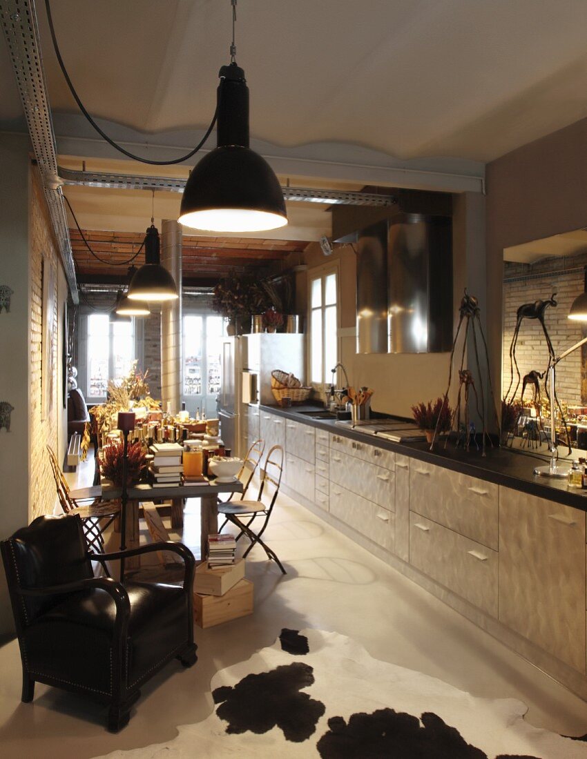 Küchenzeile an Wand, über die gesamte Zimmerlänge, gegenüber Essplatz mit Vintage Hängeleuchten in Reihe, in offenem Wohnraum