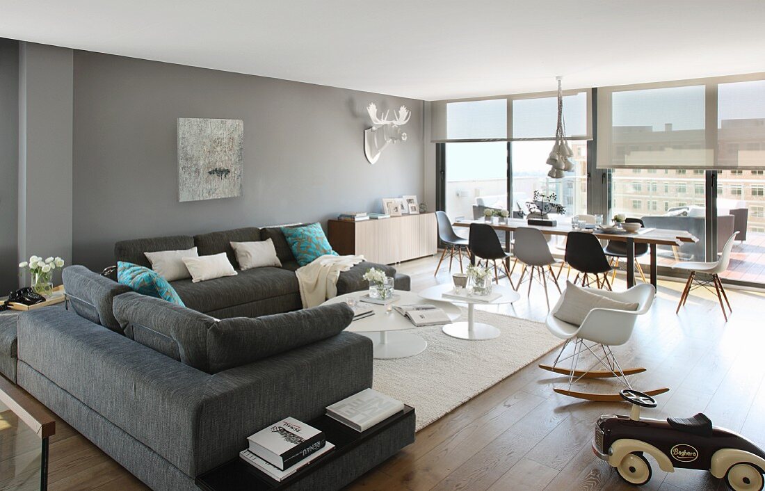 Überecksofa und Essplatz mit Klassikerstühlen von Eames in weitläufigem Penthouse-Wohnraum