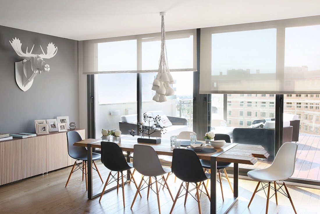 Essplatz mit Eames Chairs vor Fensterfront in Penthouse-Wohnung; Deko-Geweih an der Wand