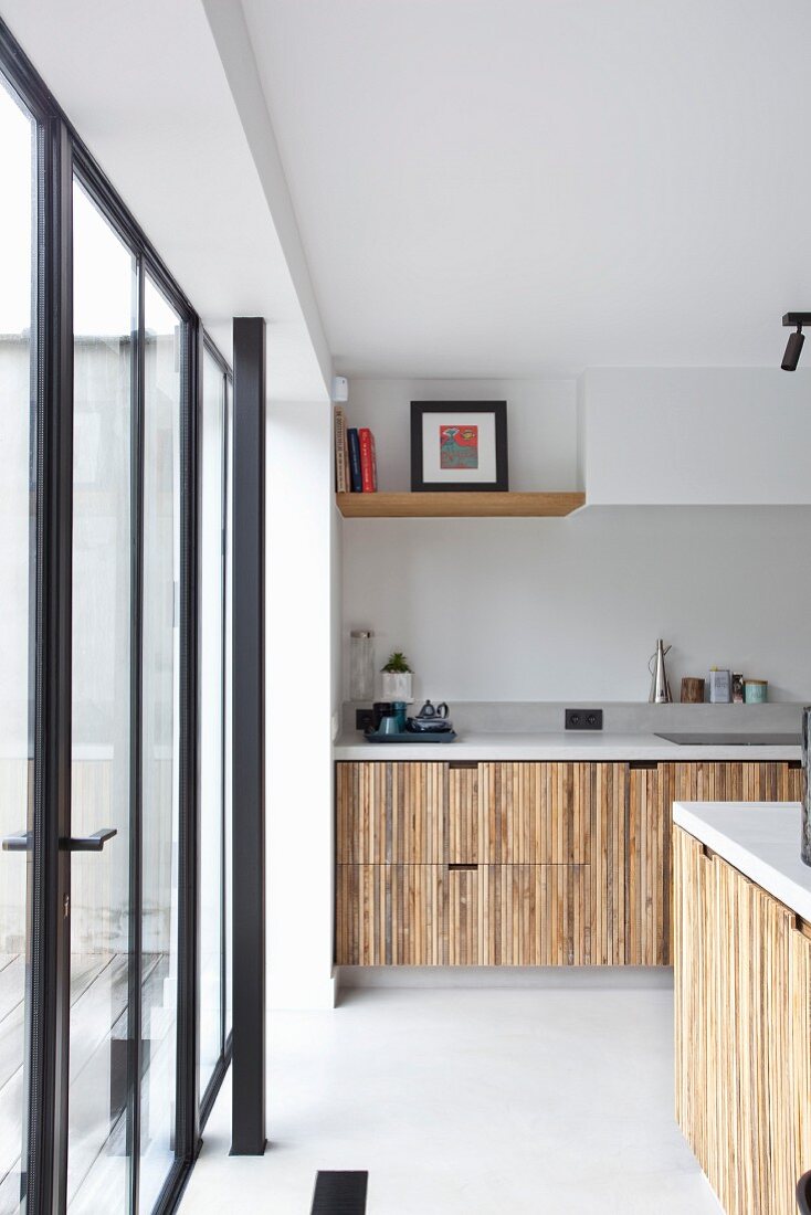 Moderne Küche mit Holzfront, seitlich Terrassentür mit schwarzem Metallrahmen