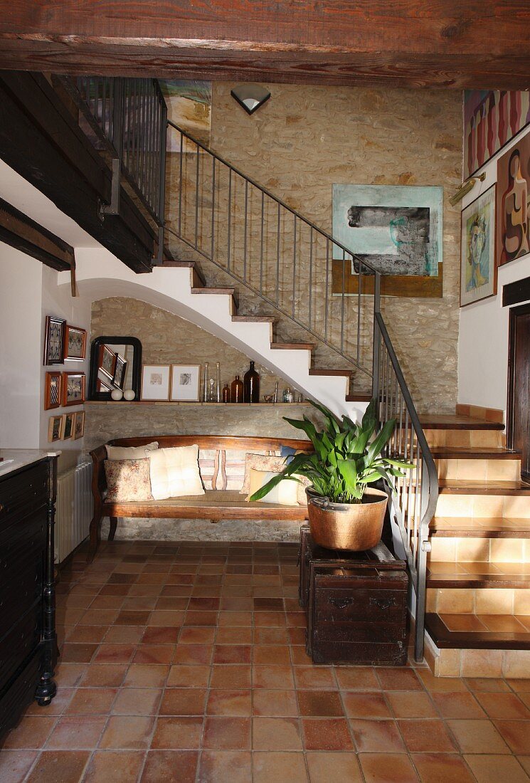 Geflieste Diele mit Sitzbank neben Treppenaufgang in traditionellem, spanischem Natursteinhaus