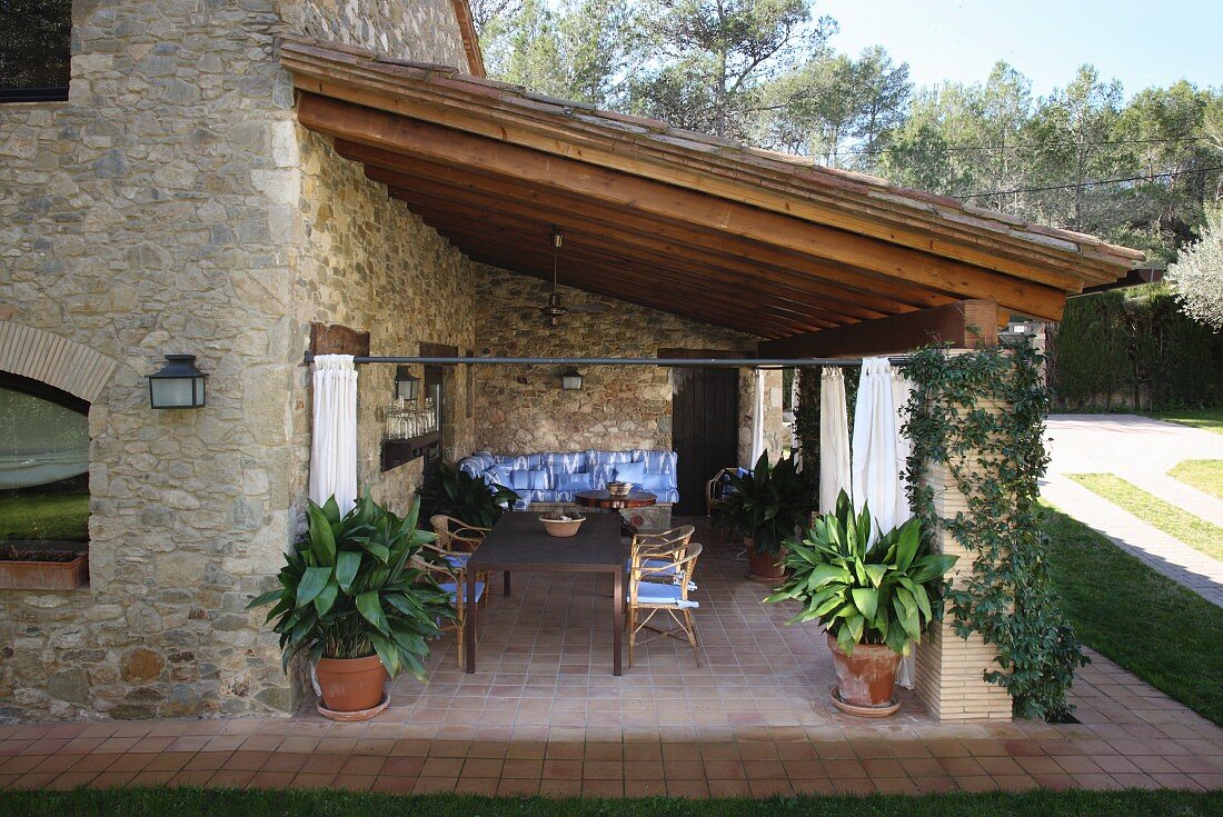 Dining area on roofed terrace of Spanish stone house