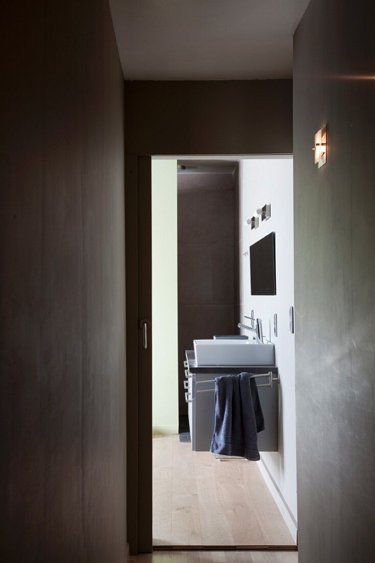 View along narrow corridor into bathroom with modern washstand