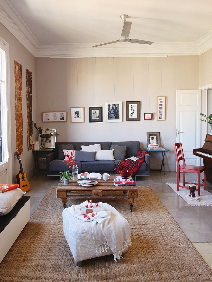 Loungebereich mit weißem Hocker, Bodentisch aus Holzpalette und graue Couch in offenem Wohnzimmer mit traditionellem Flair