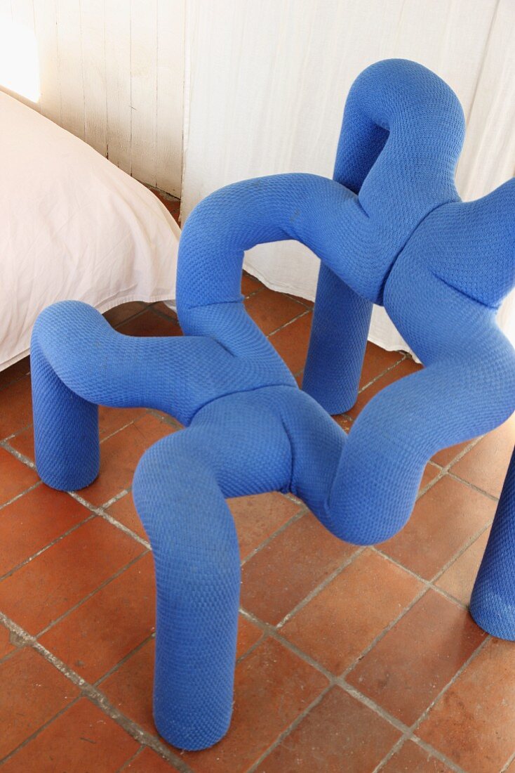 Designerstuhl aus blauen Polsterröhren auf Terracottafliesen