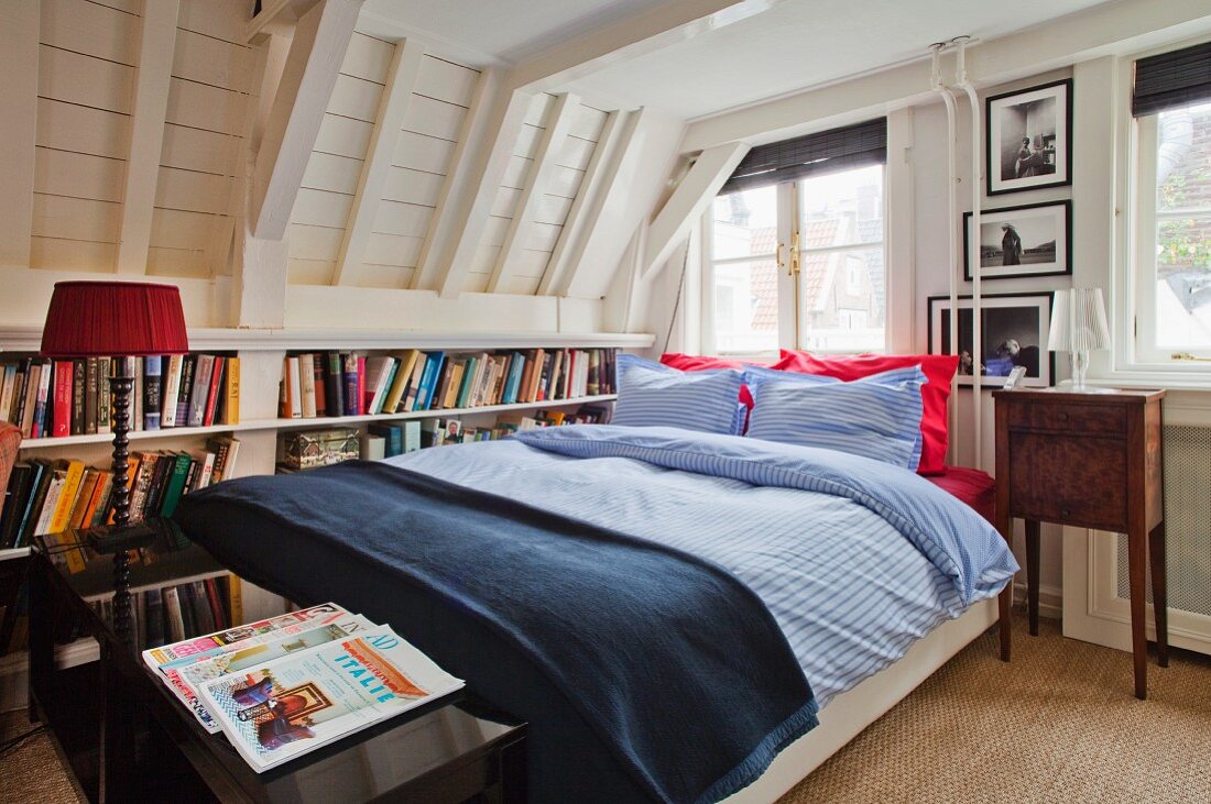 In den Kniestock eines Dachraumes eingebautes Bücherregal hinter einem Doppelbett