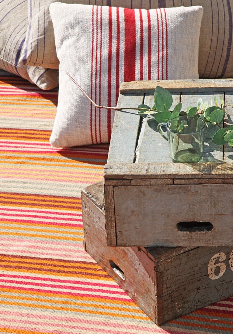 Stacked vintage wooden crates and striped cushions on striped rug