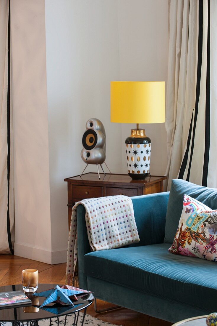 Blue sofa next to table lamp on antique table