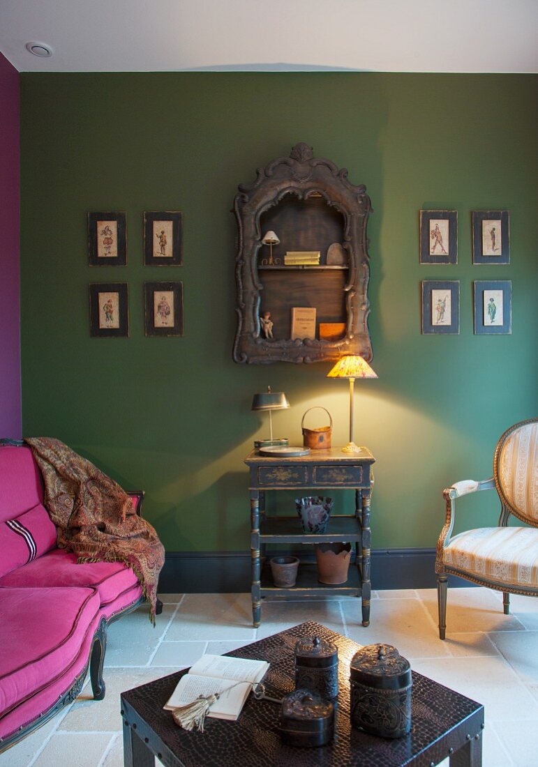 Pink sofa, lamp on console table and green-painted wall in lounge