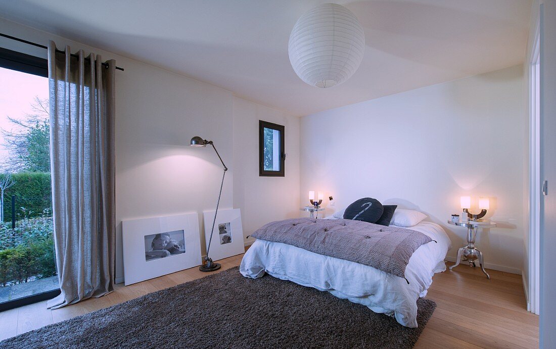 Minimalistisch eingerichtetes Schlafzimmer mit Bett ohne Rahmen, zwei silberne Nachttische aus Metall