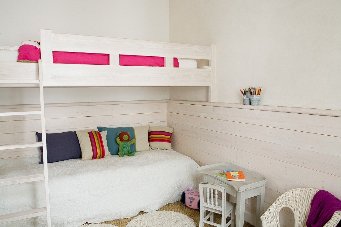 Bunk-beds with ladder, children's chair and table and wainscoting in white bedroom