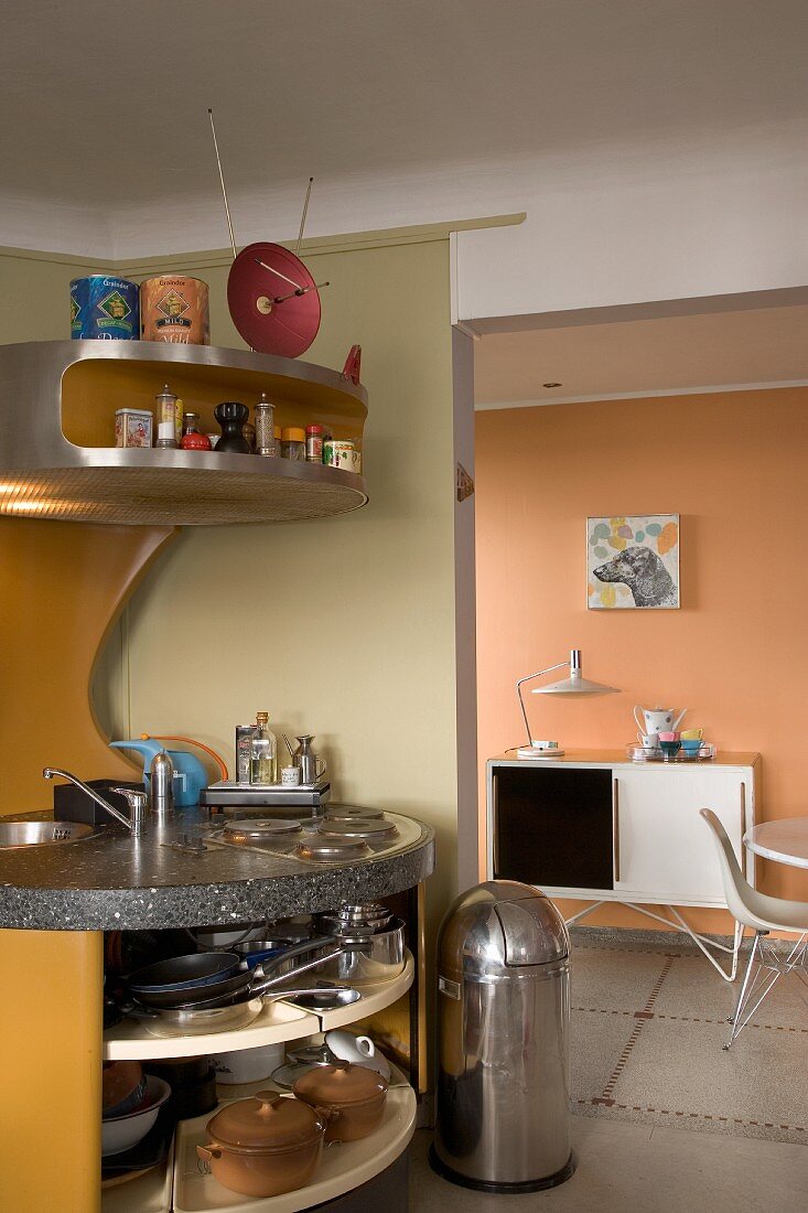 Unique retro kitchen with curved installations, open-fronted carousel shelves and stainless steel bin