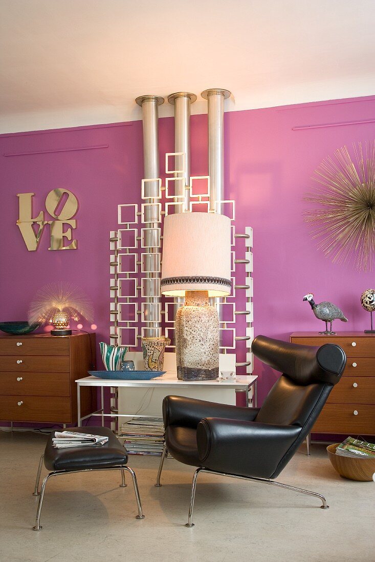 Wohnzimmer im Retrostil mit einer lilafarbenen Wand, Kunstobjekten und einem Ox Chair