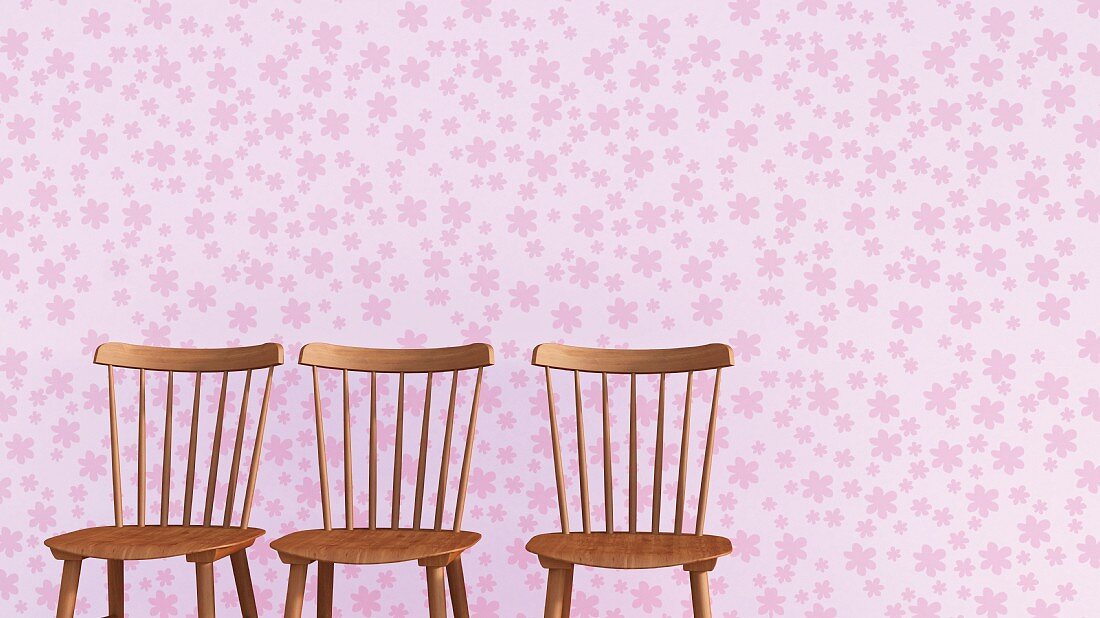Drei Holzstühle vor fliederfarbener Tapete mit Blütenmuster