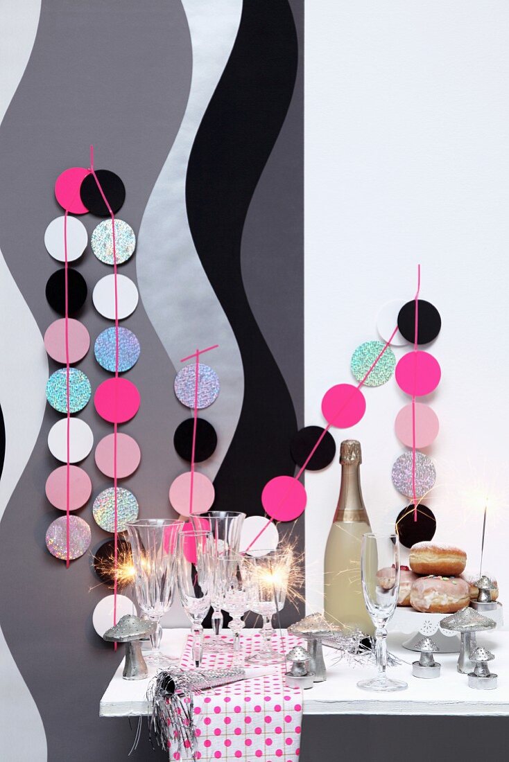 New-Year buffet with sparkling wine, sparklers and garlands of pastel circles decorating wall with grey and black pattern