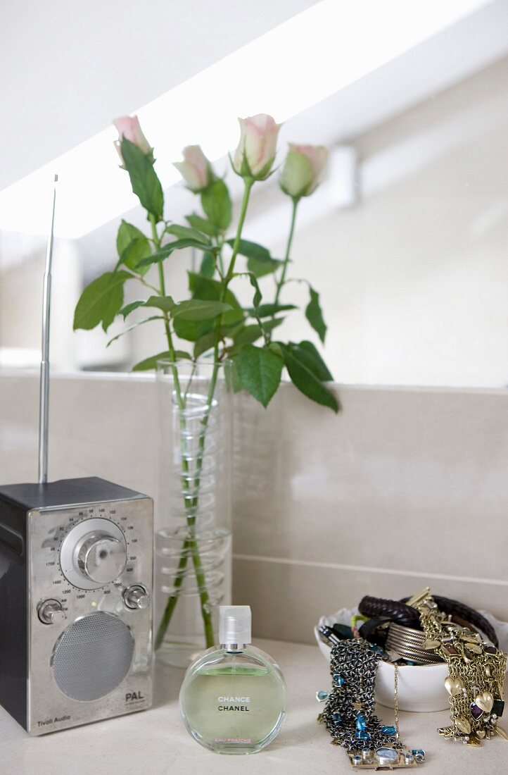 Roses, radio, perfume and bowl of jewellery on washstand