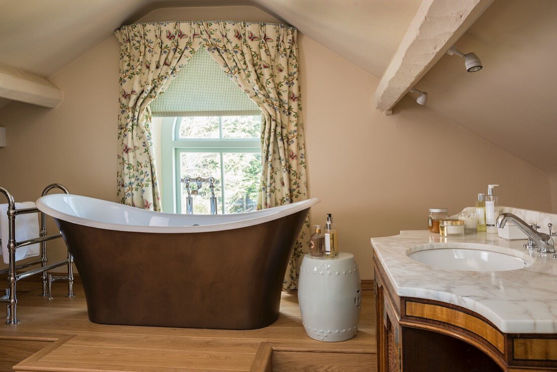 Badezimmer unter dem Dach mit freistehenden Wanne, Porzellanhocker und Waschtisch aus Marmor