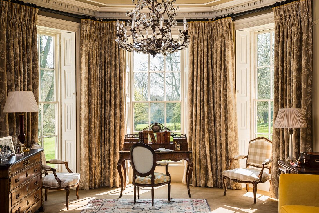 Classic desk and Baroque chairs in window bay with lattice windows and opulent curtains