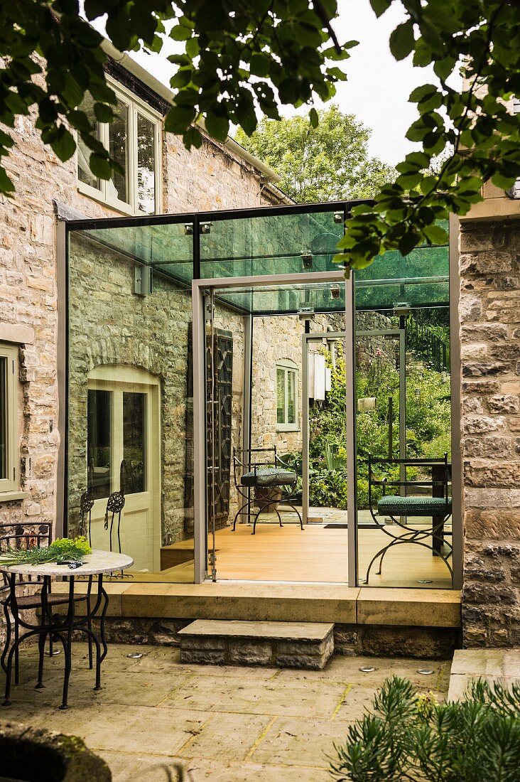 Modern angebauter Wintergarten an ein englisches Landhaus aus Stein