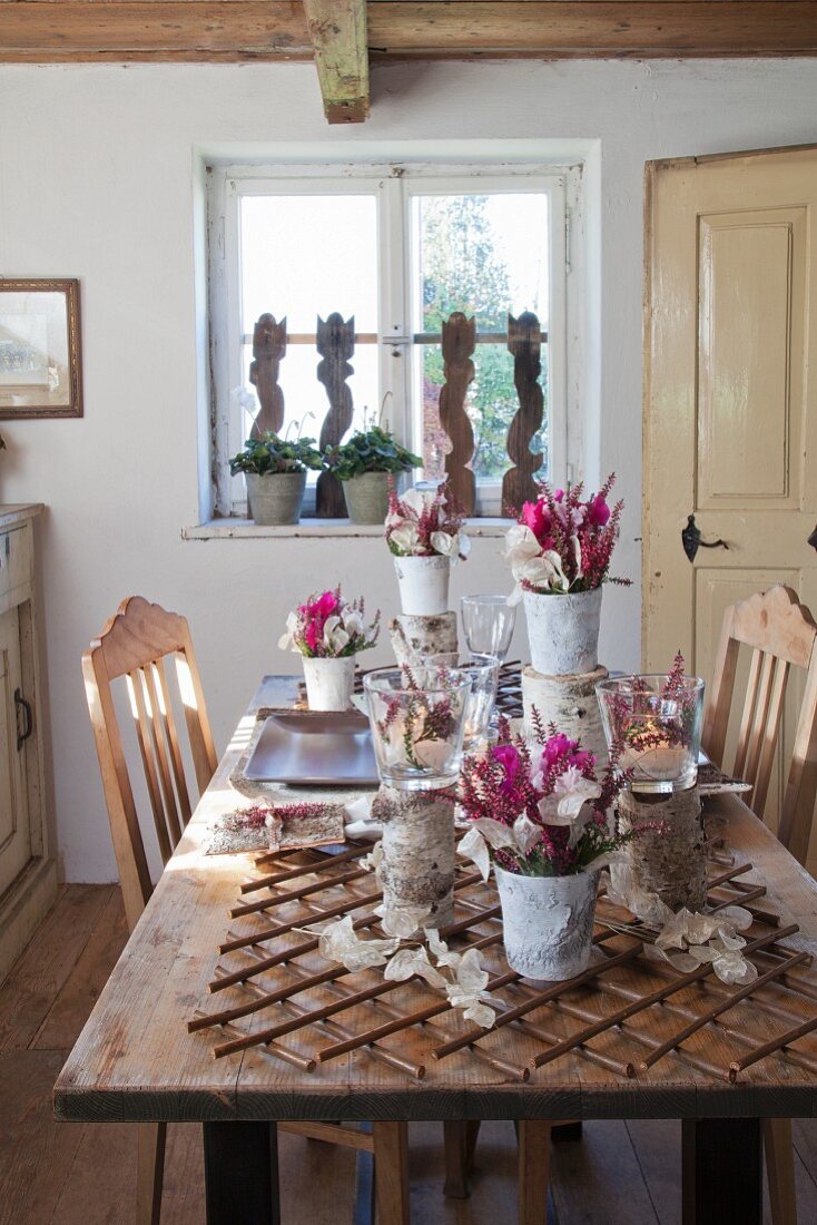 Mit Naturmaterialien dekorierte Vasen und Blumengestecke auf rustikalem Tisch in bäuerlichem Esszimmer