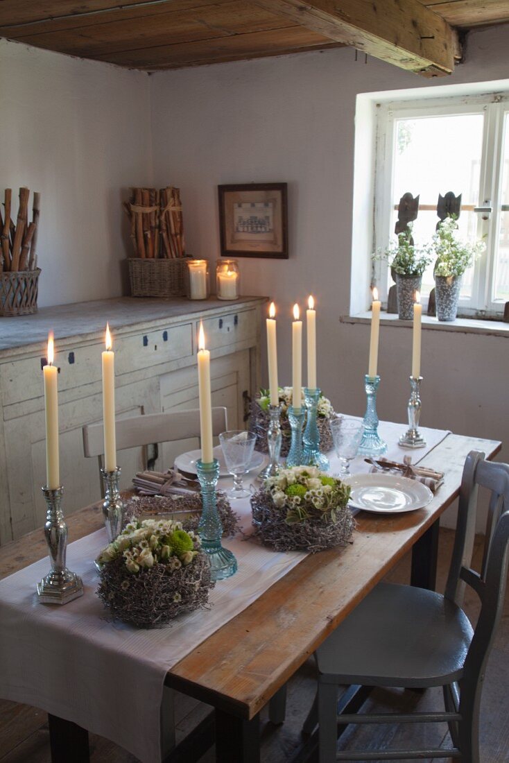 Candlesticks and wreaths on rustic wooden table with runner