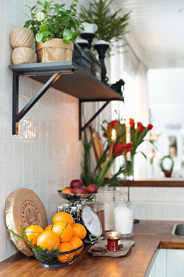 Wandbord mit Pflanzen über Küchenzeile mit Holzarbeitsplatte, Korb mit Orangen