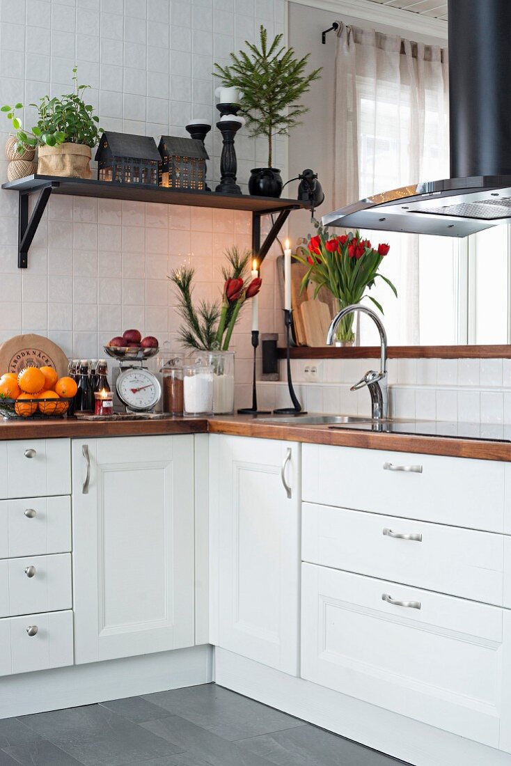 Festive flower arrangements on white kitchen counter and house lanterns on bracket shelf