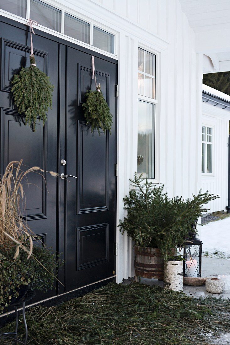 Adventliche Deko mit Tannenzweigen auf der Veranda eines skandinavischen Hauses