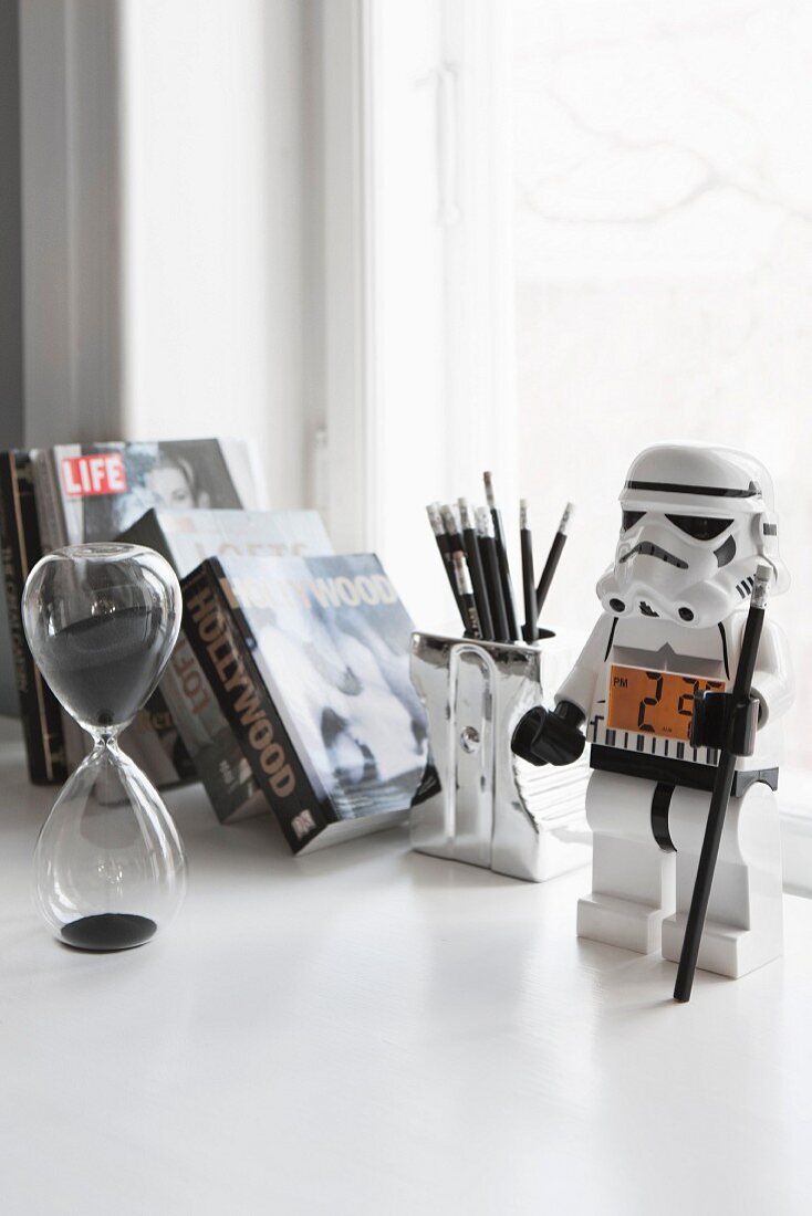 Glass hour glass and stormtrooper toy on desk